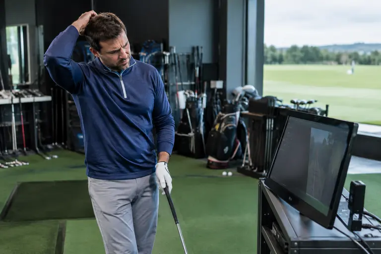 Clubface impact pattern being checked after shots on a range mat