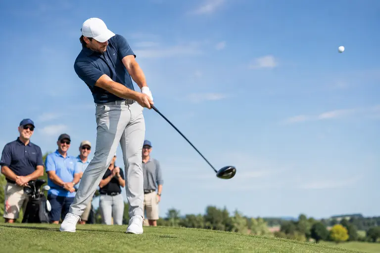 Launch monitor beside a golfer hitting a wood during a fitting session