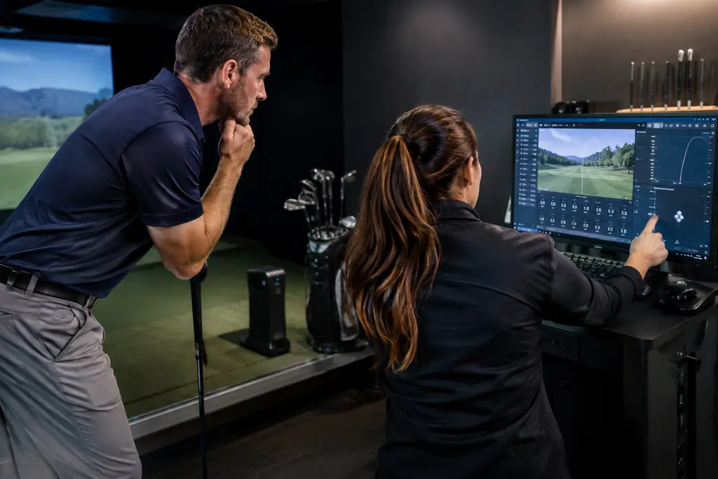 Golfer checking launch monitor price cuts on a tablet beside clubs